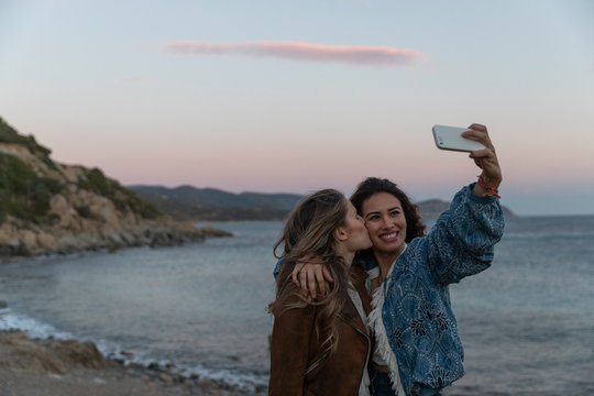 Two girls taking a selfie together by the sea