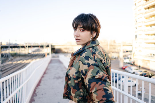 Stylish brunette in camouflage jacket on street