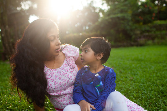 Mother talking with her little daughter sitting in the lawn