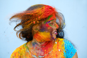 Young woman playing with her hair full of color powder during holi celebration