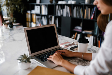 Crop lady using laptop in modern library