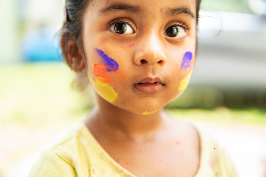Portrait Of Cute Little Girl smudged Colored Powders During Holi