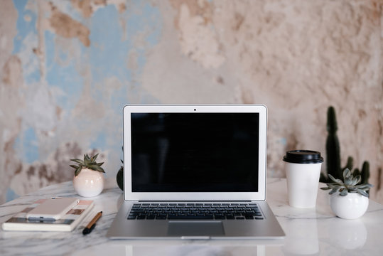 Laptop and hot beverage near shabby wall