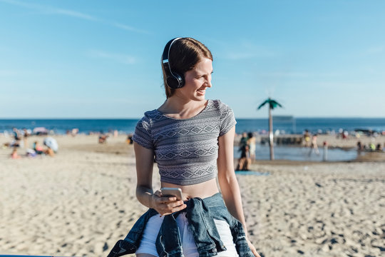 Young Beautiful Smiling White Woman Portrait Using a Cell Phone Listening Music With Headphones. Lifestyle Stock Picture
