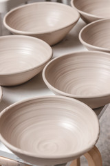raw ceramic bowls made from white clay on the potter's wheel circle waiting for putting in the...