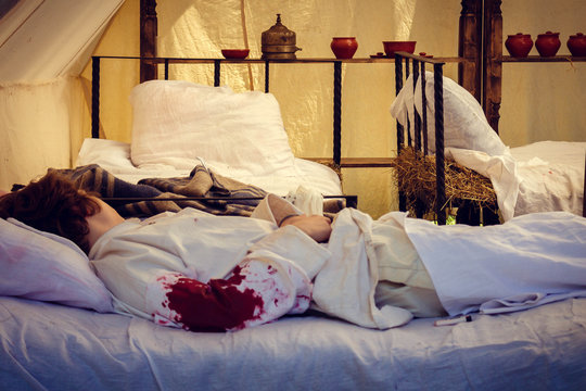 A Wounded Soldier Of The First World War Lies In A Field Hospital. Hand In Blood