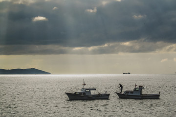 Fishermen with their boats on the Bosphorous strait are manouvering on the sea on a cloudy but still sunny day.