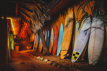 A collection of different colorful surf boards used as a decoration next to a walkway, resting on a...