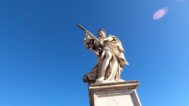 Statue of an angel holding a cross against the blue sky, Rome, Italy. 4k