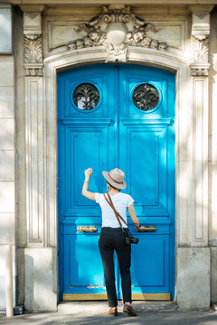Unrecognizable woman knocking at blue door