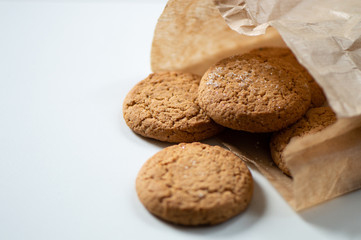 Sweet round cookies in brown paper bag on white table