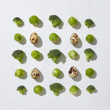Food pattern of quail eggs, broccoli and brussels sprouts on a gray background with copy space. Healthy food. Flat lay