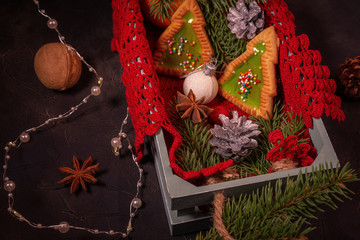 This is a magical Christmas dark red background: beautiful cookies in the form of a Christmas tree, fir twigs, Christmas decorations, beads, cones, nut. The concept of new year and Christmas holidays