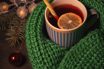 Christmas Christmas magic a dark background. This is a red drink, which is filled with a ceramic Cup wrapped in a warm scarf. The concept of winter, solitude, Christmas, warmth and comfort.