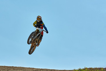 Extreme sports, motorcycle jumping. Motorcyclist makes an extreme jump against the sky. Film grain effect, illumination