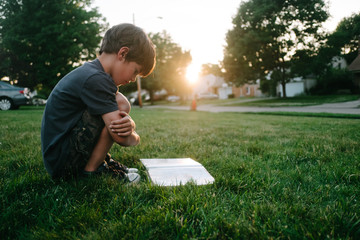 boy reading on grass in sun