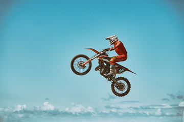 Extreme sports, motorcycle jumping. Motorcyclist makes an extreme jump against the sky. Film grain...
