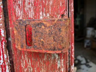 Rusty Lock Hinge on Door With Peeling Red Paint