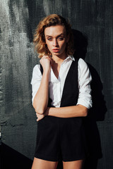 portrait of a beautiful fashionable blonde woman in black shorts white blouse