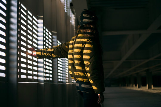 an unfamiliar girl stands in an abandoned parking lot in the shade
