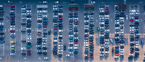 Bird's eye aerial view from drone parking lot with colored cars on a gray asphalt background. Top view strictly above.