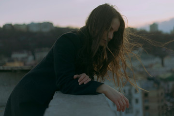 atmospheric portrait of a girl on the roof at black coat