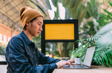 Asian tourist working on laptop using the free wifi of the train station