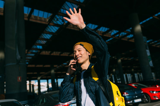 Chinese young man using a cellphone in the parking lot and calling a taxi