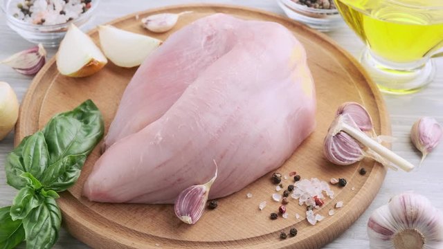 Raw turkey fillet on a cutting wooden board with spices, garlic, salt, pepper. Culinary concept. G