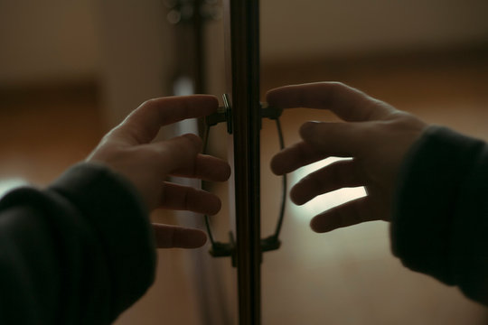 man's hand opens the door and its reflection in the mirror