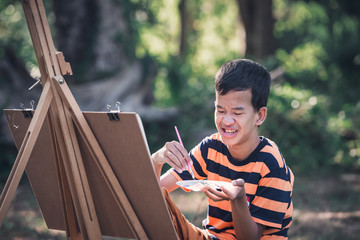Asian boy with Down's syndrome is happily drawing a picture of an elephant in the garden.Drawing,...