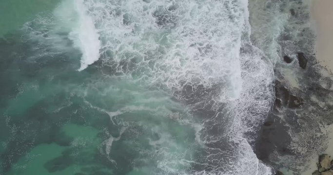 Aerial view of the waves crashing towards the beautiful white sand beach, raw footage, ungraded, no color, log profile