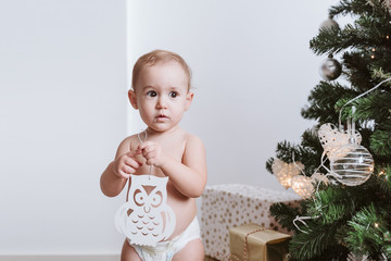 cute baby girl wearing diaper decorating Christmas Tree