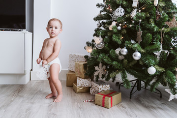cute baby girl wearing diaper decorating Christmas Tree