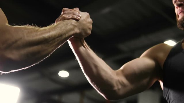 Confident male athletes shaking hands before competition, rivalry, slow-motion