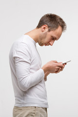 Close up portrait of man looking and using smart phone with scoliosis, side view, isolated on gray...