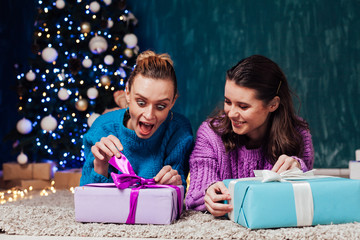 Two women open gifts at the Christmas tree for the new year