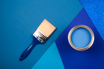 Brush on open can of blue paint on blue background. Color of the year in interior.