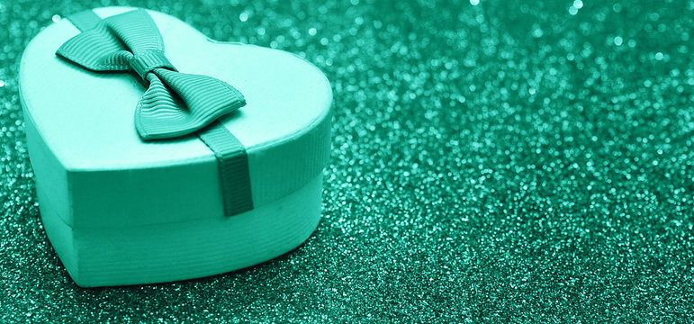 Gift heart box on sparkling glitter paper background.