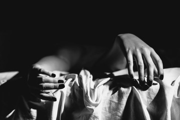 Close up on female young woman's girl's beautiful hands woman lying on the bed black and white nail...