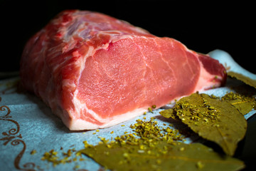 raw pork loin on a dark background and Bay leaves