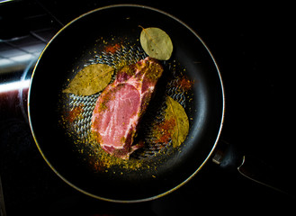 raw steak in a pan with seasonings