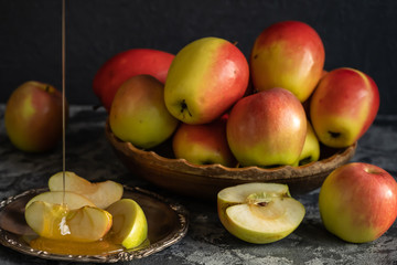 Fresh apples on a wooden plate, sliced apples on a metal plate with honey