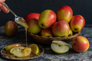 Fresh apples on a wooden plate, sliced apples on a metal plate with honey