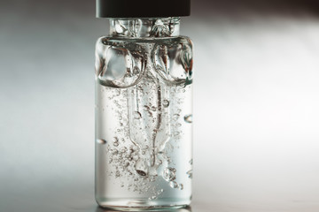 Bottle of hyaluronic acid with pipette on silver background. Front view.