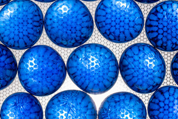 Blue oval and round pieces of glass are illuminated through a textured background