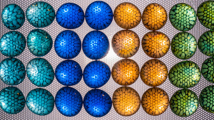 Multicolored oval and round pieces of glass are illuminated through a textured background