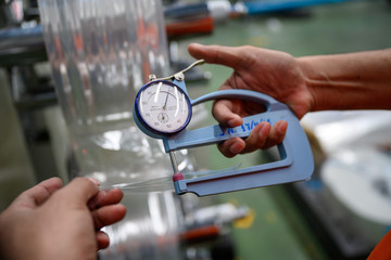 Man's hand is measuring the thickness of the plastic bag type film Polypropylene To check and...