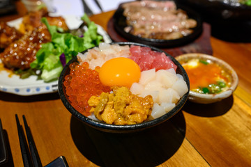 Top View Donburi 5 Types with Raw Eggs on a Black Bowl in a Japanese Restaurant.