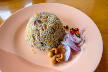 Salted chinese black olive fried rice with minced pork In a light red dish on an orange wooden...